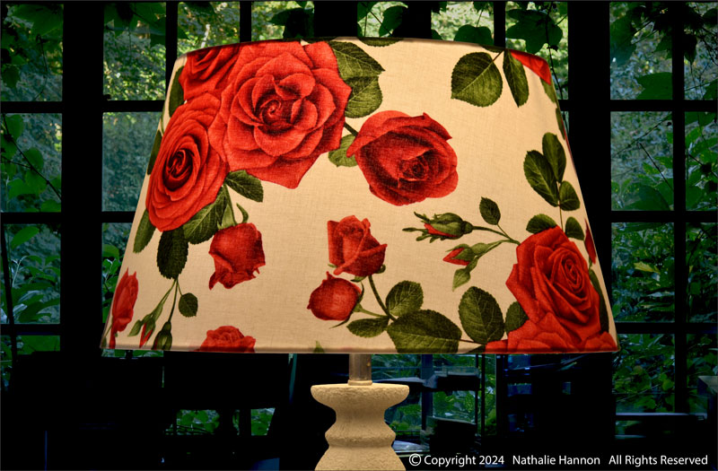 Éclairage de décoration pour luminaire de forme tambour sur pied de lampe en tissu à motif de grandes fleurs roses rouges.