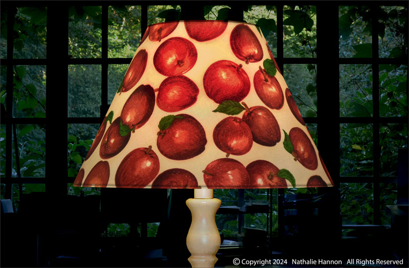 Éclairage d'un conique décoratif pour pied de lampe en tissu coton imprimé fruits pommes rouges.