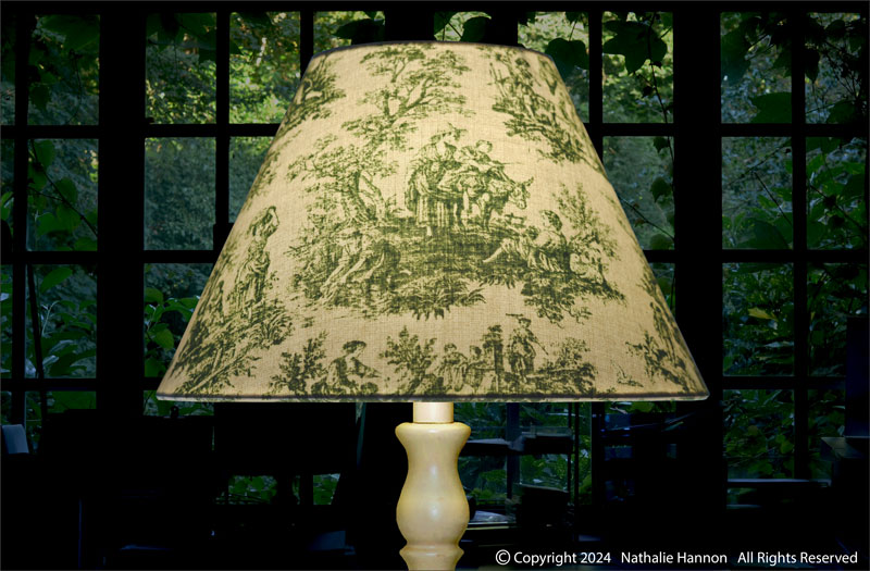 Éclairage décoratif d'un petit conique sur pied de lampe en tissu imprimé inspiration toile de Jouy couleur vert.